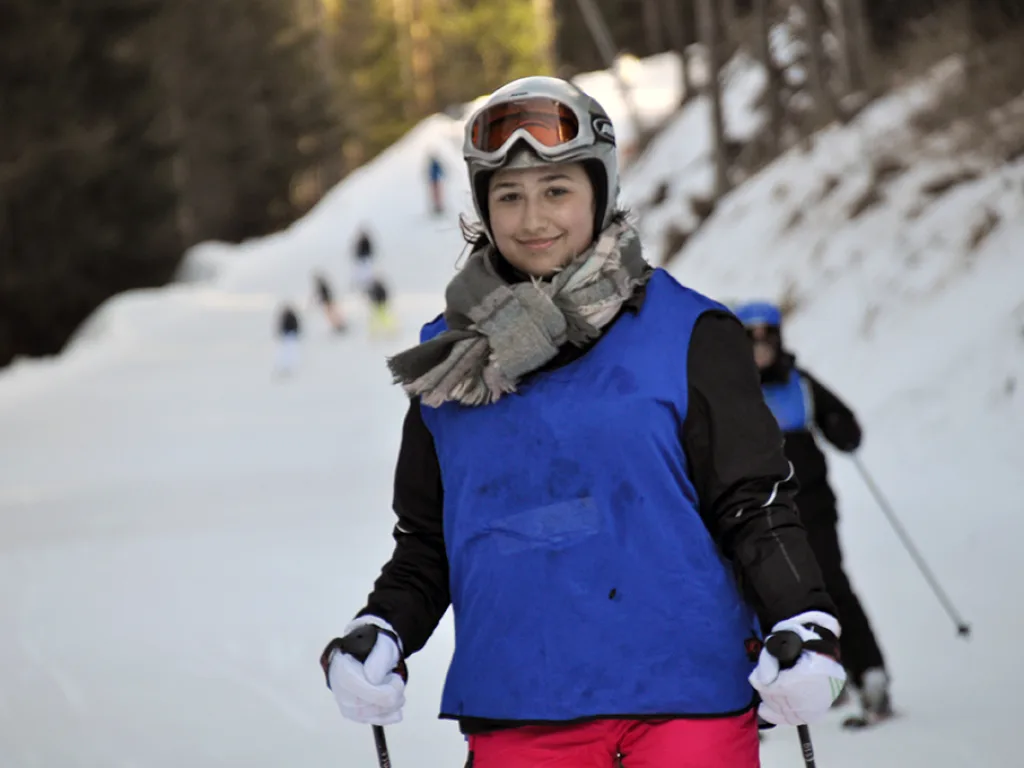 Skifahrerin mit Schal und Skibrille auf der Piste.